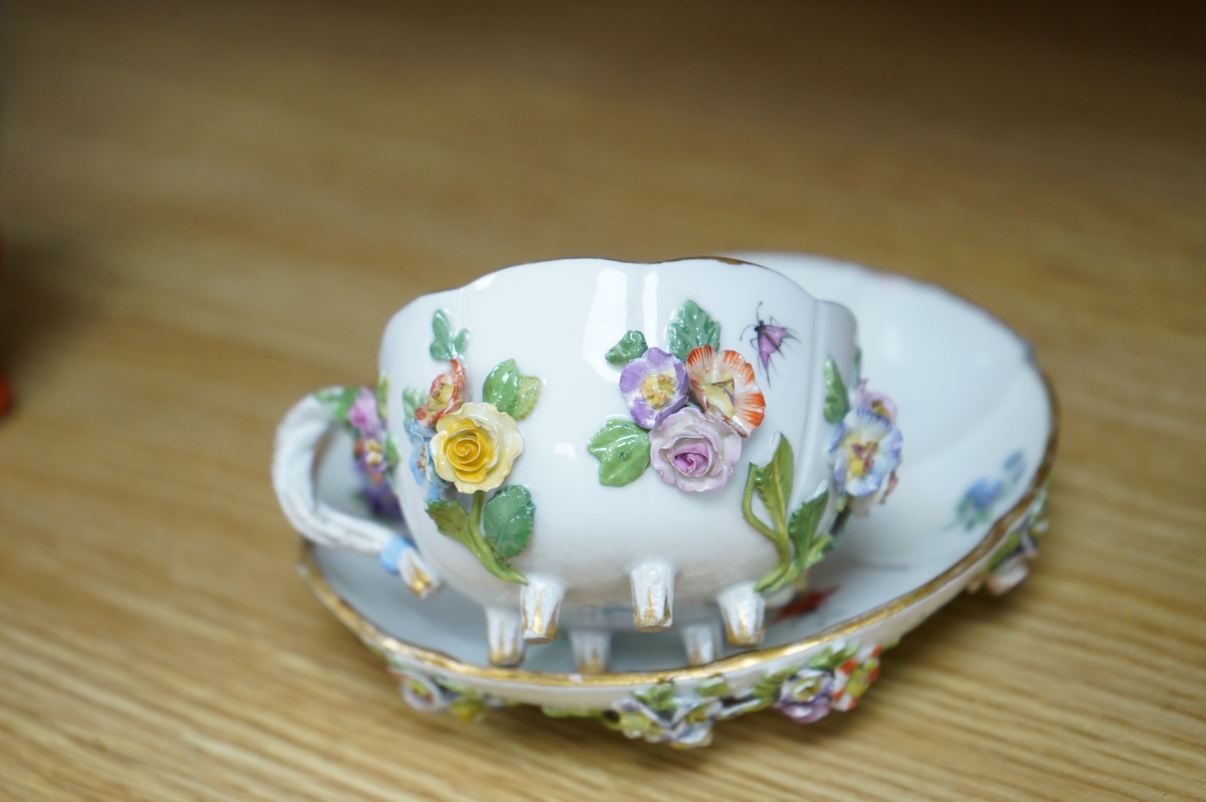 A 19th century Meissen floral encrusted cup and saucer, 14cm diameter
